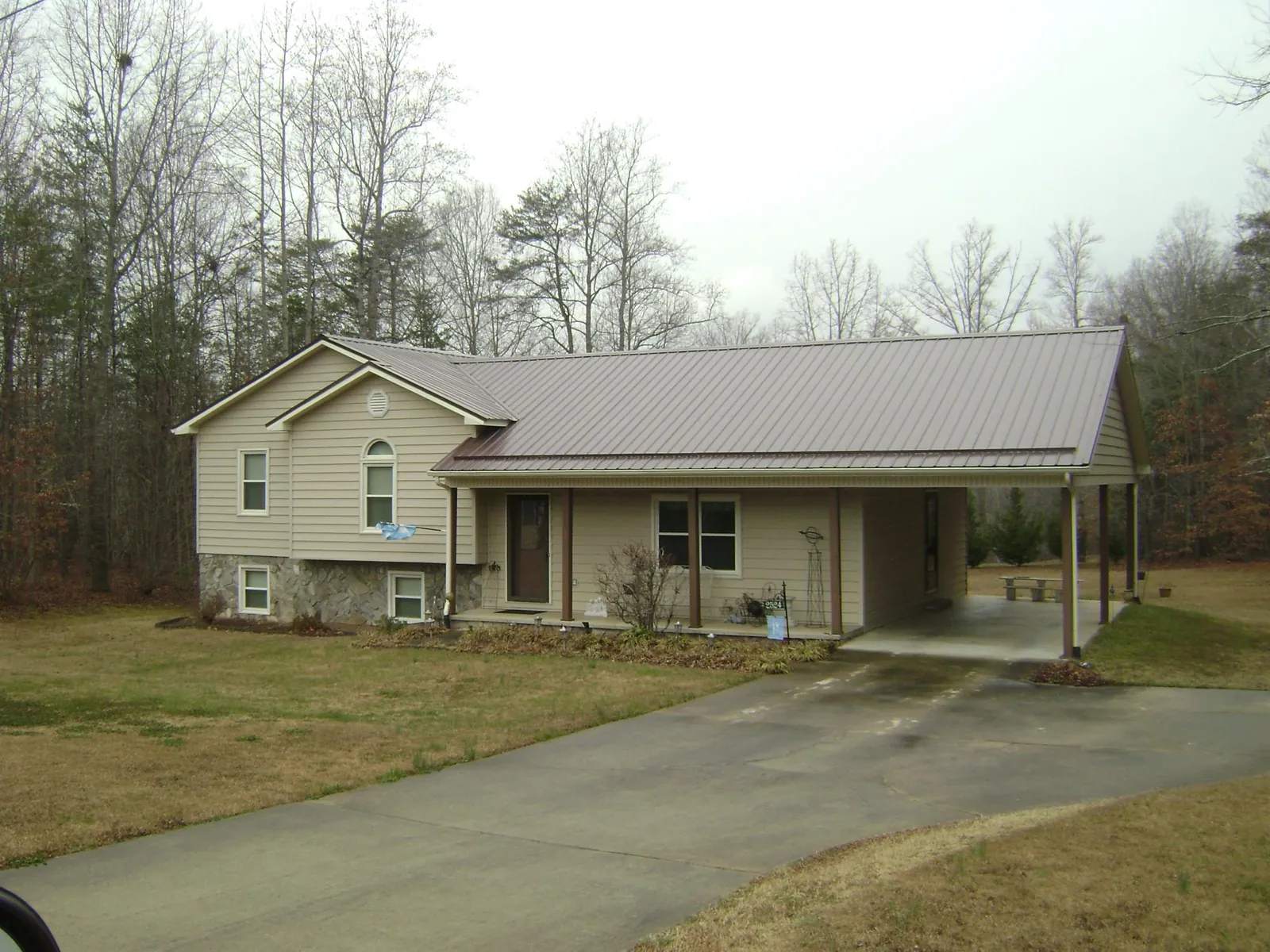 Brown metal roof on a tan split level home with an attached carport in Jamestown